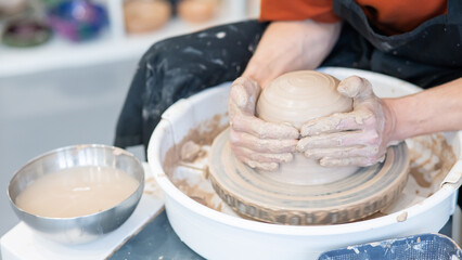 Close-up of a potter's hands working on a pottery wheel. 