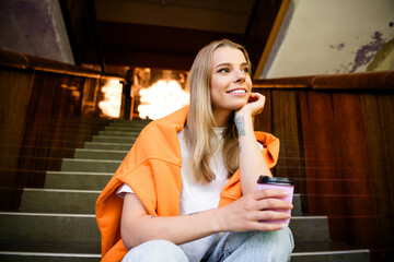 Photo of adorable sweet lady wear white t-shirt sitting stairs enjoying coffee indoors campus hall