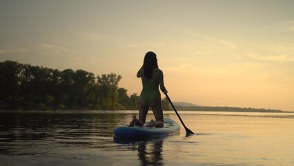 A beautiful silhouette of a person paddleboarding during a serene sunset by the lake