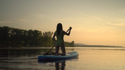 A beautiful silhouette of a person paddleboarding during a serene sunset by the lake