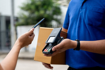 A customer tapping her smartphone on a card reader before receiving a package from a delivery man.