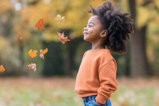 African little girl smiling wearing sweatshirt playing at sunny autumn park