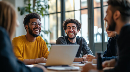 diverse group of people are laughing and working together in an office meeting room with a laptop on the table