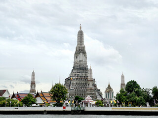 Naklejka premium Wat Arun, or the Temple of Dawn, a famous temple site with its unique spires and sculpted stones, located alongside Chao Praya river in the heart of Bangkok, Thailand.