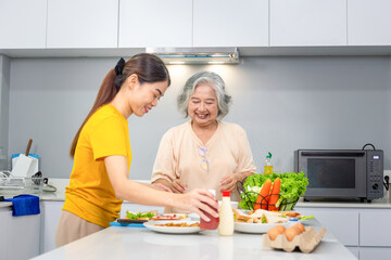 Senior asian mother and middle aged daughter cooking together at kitchen