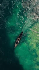 Obraz premium High angle view of a wooden boat with a lone individual on a tranquil green river, creating a serene scene.