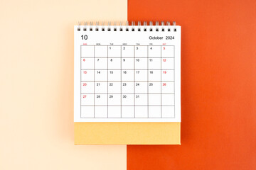 Directly above view of October 2024 desk calendar on orange background.