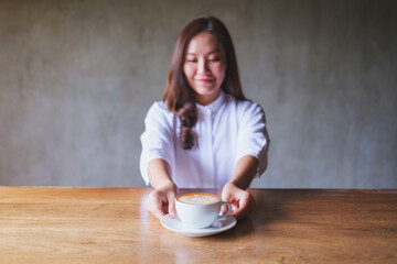 Portrait image of a woman holding and serving a cup of hot coffee