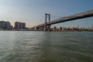Taken from a ferry on the way to New York City, this picturesque view captures the calm waters, with the city's towering skyline illuminated by the city's lights. The Manhattan Bridge stands prominent
