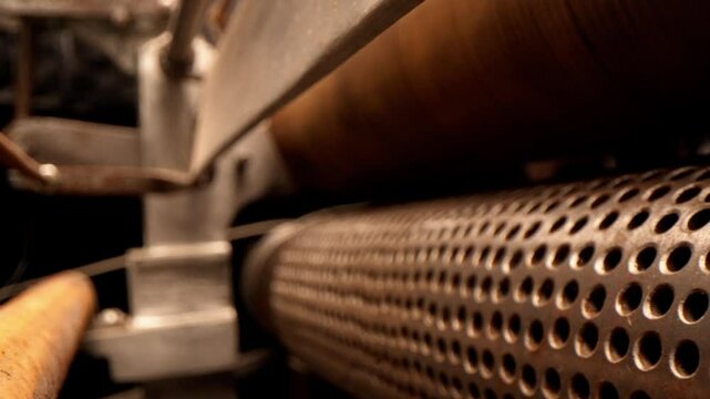 Obsolete paper press machine with perforated drum and rollers in workshop closeup. Old machine for papermaking in technology museum