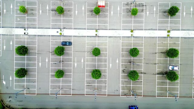 This is an aerial photograph capturing a nearly deserted parking lot that showcases a layout of evenly spaced trees