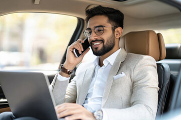 young indian businessman working on laptop in car