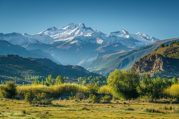 Fototapeta premium A tranquil mountain vista with snow-capped peaks rising majestically against a clear blue sky, the lower slopes softly blurred to evoke a sense of holiday tranquility