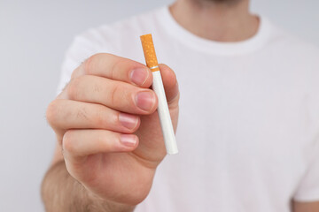 A cigarette in a man's hand on a light background
