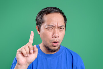 Fototapeta premium Young Asian Man Showing No Sign With Index Finger Over Green Background
