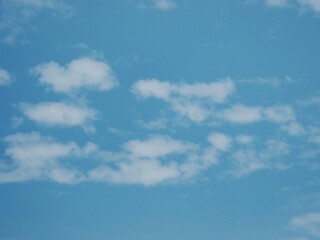 Obraz premium This image depicts a clear blue sky with white, wispy clouds. The sky is a vibrant blue color, contrasting with the lighter tones of the clouds. The clouds are thin and delicate, creating a sense of o