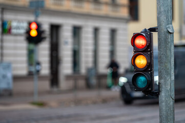 view of city traffic with traffic lights, in the foreground a semaphore with a red and orange light