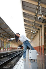 A woman is standing on a train platform with her luggage