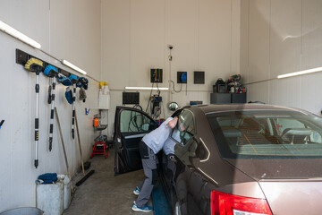 Side view of young male mechanic examining car at auto repair shop