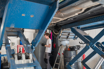 Side view of young male mechanic examining car at garage