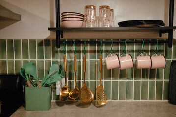 Kitchen countertop with utensils, mugs, and neatly stacked dishes.