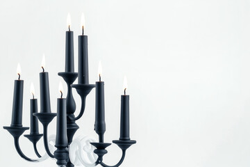 Black candles in stylish holders on a plain white background. Minimalistic display for home Halloween decor concepts