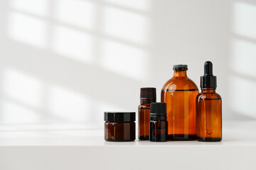 Collection of Amber Glass Bottles and Jars for Essential Oils on a White Surface