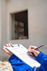 An architect is checking on house building quality checklist form to inspecting the progress with...