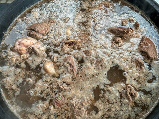 The meat is cooked in a cauldron over a fire
