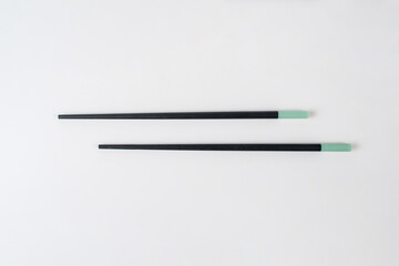 Black chopsticks for rice on a white background