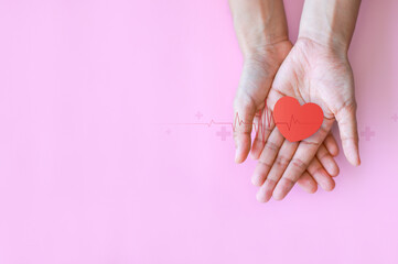 Hand hold heart shape on pink background for health care checking the function of the patient...