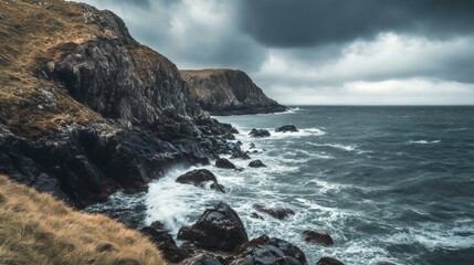 Fototapeta premium Rocky coastline with crashing waves under a stormy sky.