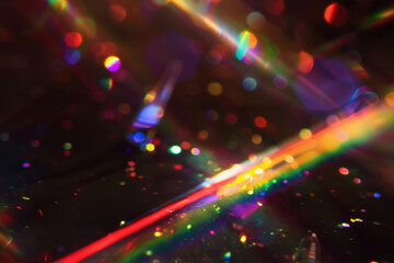 Obraz premium Abstract light beams in vibrant colors, bokeh and sparkling particles overlay on dark background. Rays of light, rainbow crystal glass light refraction effect.