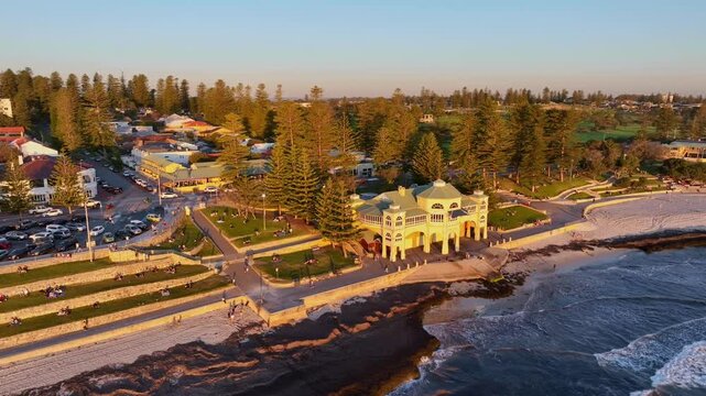 People enjoy sunset on Cottesloe Beach foreshore at sunset near famous building, Perth, Western Australia