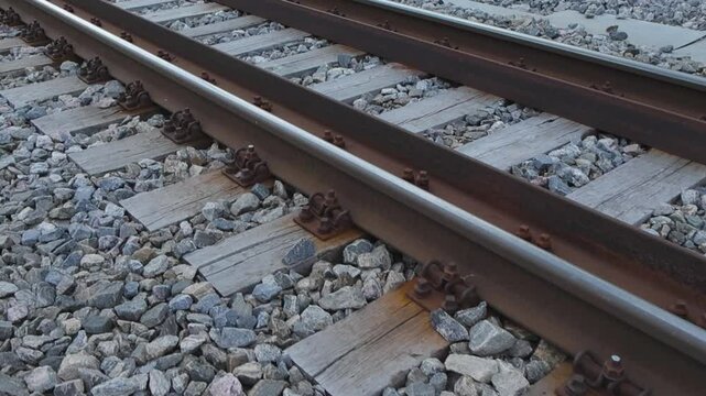 Footage of railroad tracks during the summer time in Estonia Laagri P&auml;&auml;sk&uuml;la. Tracks are laid on thick and big wooden blocks and granite gravel stones and rocks are on the sides. Appears to be cloudy.