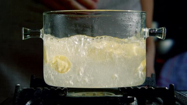 Glass pot boiling water with ravioli on kitchen stove