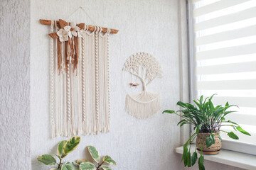 Wall hanging macrame hand made on white wall. ECO friendly modern knitting DIY natural decoration concept in the interior. Handmade 100% cotton, female hobby.