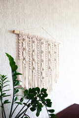 Close-up of hand made macrame texture pattern. ECO friendly modern knitting DIY natural decoration concept in the interior. Handmade 100% cotton, female hobby.