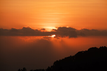 Sunset behind clouds and silhouetted hills