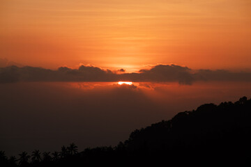 Sunset behind clouds and silhouetted hills