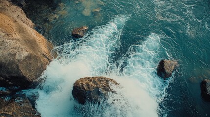 Obraz premium Top view of the stunning Kulen Mountain Waterfall, with cascading waters flowing over large rocks into a crystal-clear pool.