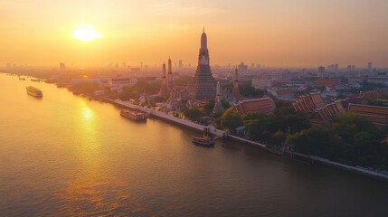 Fototapeta premium Top view of the Wat Arun temple on the banks of the Chao Phraya River, bathed in the golden light of dawn.