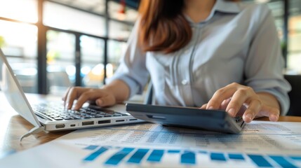 Close up businesswoman hand using calculator and working with laptop to calculate about finance accounting, market report with business document on office table