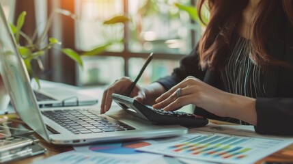 Close up businesswoman hand using calculator and working with laptop to calculate about finance accounting, market report with business document on office table