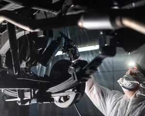 The master sprays an anti-corrosion compound on the bottom of the car. 
