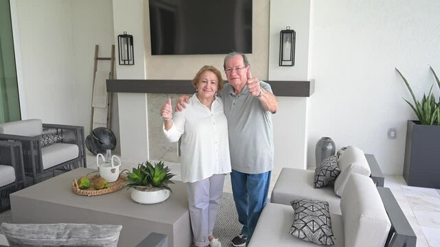 happy couple give a thumbs-up to their new modern outdoor furniture outside in their lanai area in their newly constructed home