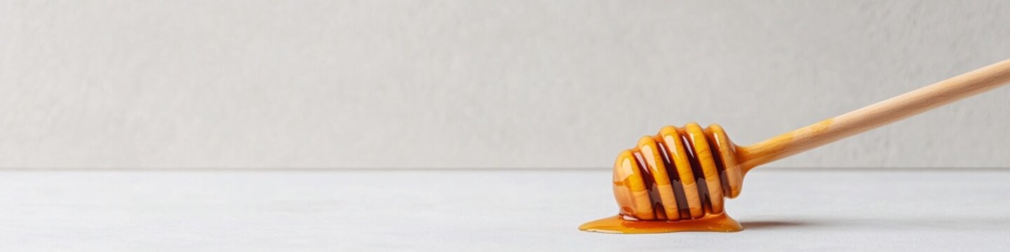 Honey dripper with liquid honey on a minimalistic background