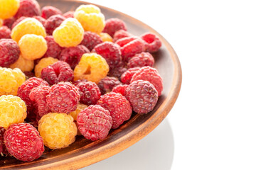 Fresh raspberry berries on a clay plate, macro, isolated on white background.
