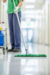 A janitor cleaning a shiny floor in a hallway, showcasing professionalism and cleanliness in a public building.