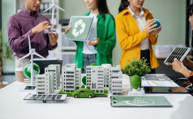 Asian professionals collaborate on sustainable energy solutions with wind turbines, solar panels, and eco friendly models